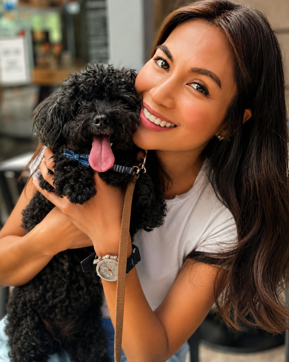 Kat, smiling, holding Ceelo — her small black poodle — against her shoulder.